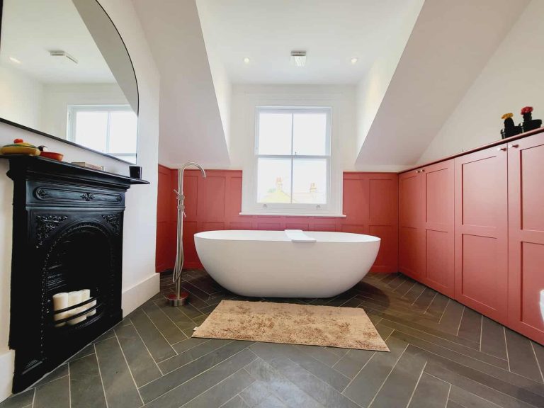 Modern Luxury Bathroom Design: Transform Luxury bathroom renovation featuring a freestanding bathtub, black fireplace, and bespoke pink cabinetry.