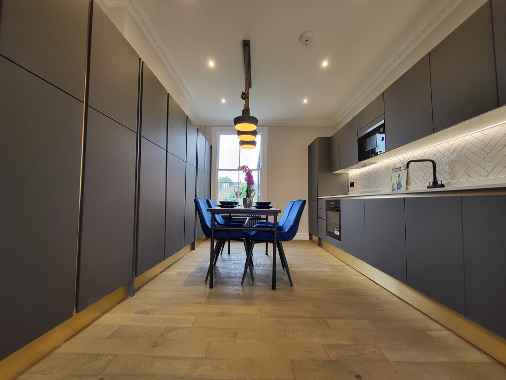 modern kitchen renovation completed by builders london with dark cabinets and dining area