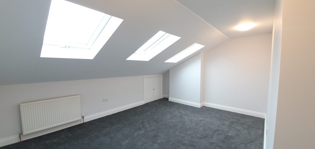 Loft conversion bedroom in Islington at Kingsdown Road N19 with roof skylights, grey carpet and built-in storage